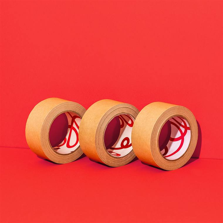 Three rolls of kraft water-activated paper tape on a red backdrop